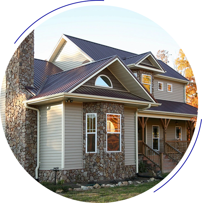 A two-story house with a mix of stone and beige siding, featuring a brown metal roof, a chimney, and a front porch.