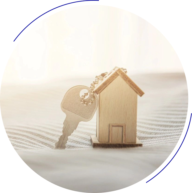 A small wooden house figurine next to a metal key on a light-colored, textured surface.