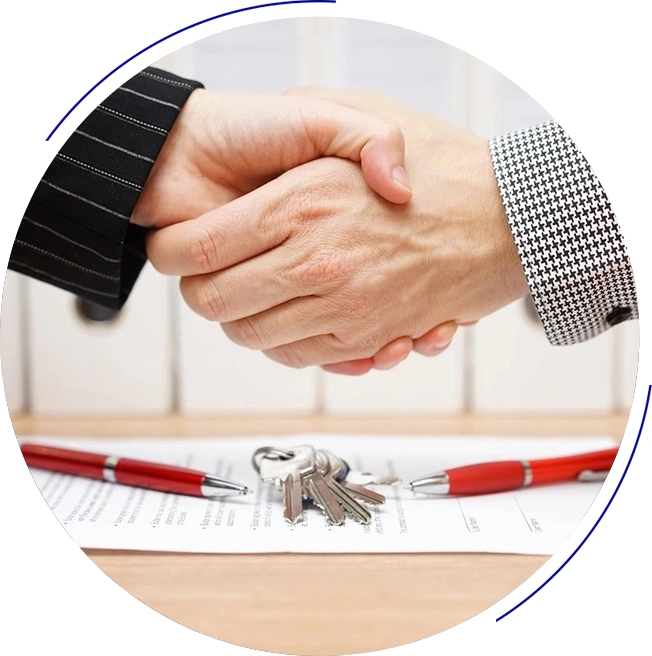 Two people shaking hands over a table with keys.