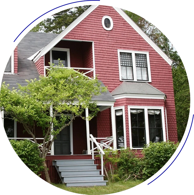 A red house with a tree in front of it.